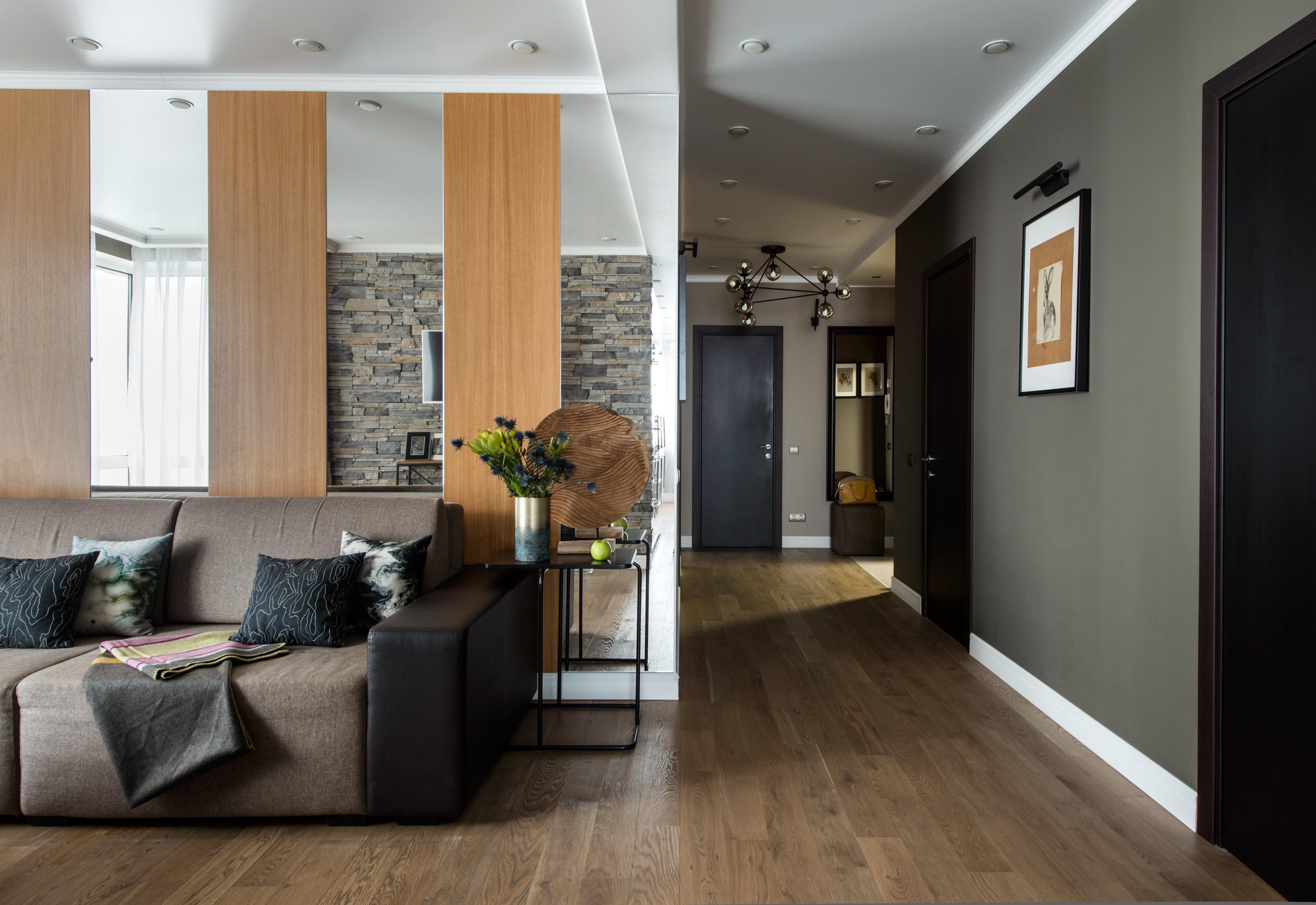 Интерьер гостиной с в деревянном доме, проходной, керамогранитом на стену с телевизором, рейками с подсветкой и подсветкой настенной