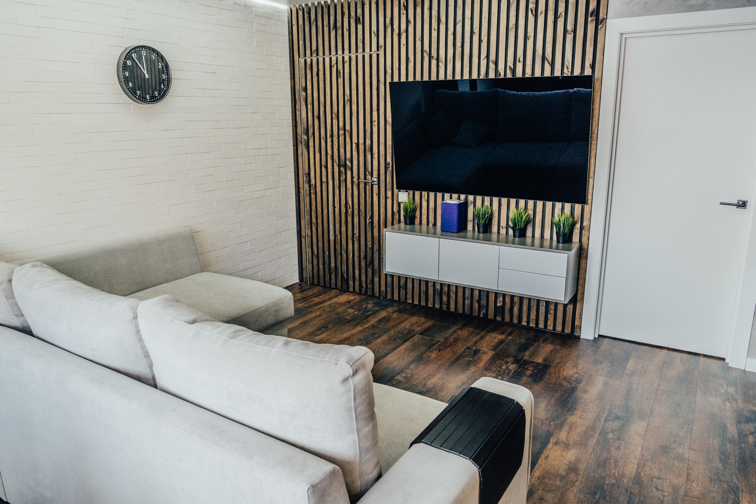 Интерьер гостиной с в деревянном доме, сауной, зонированием рейками и телевизором на рейках в современном стиле