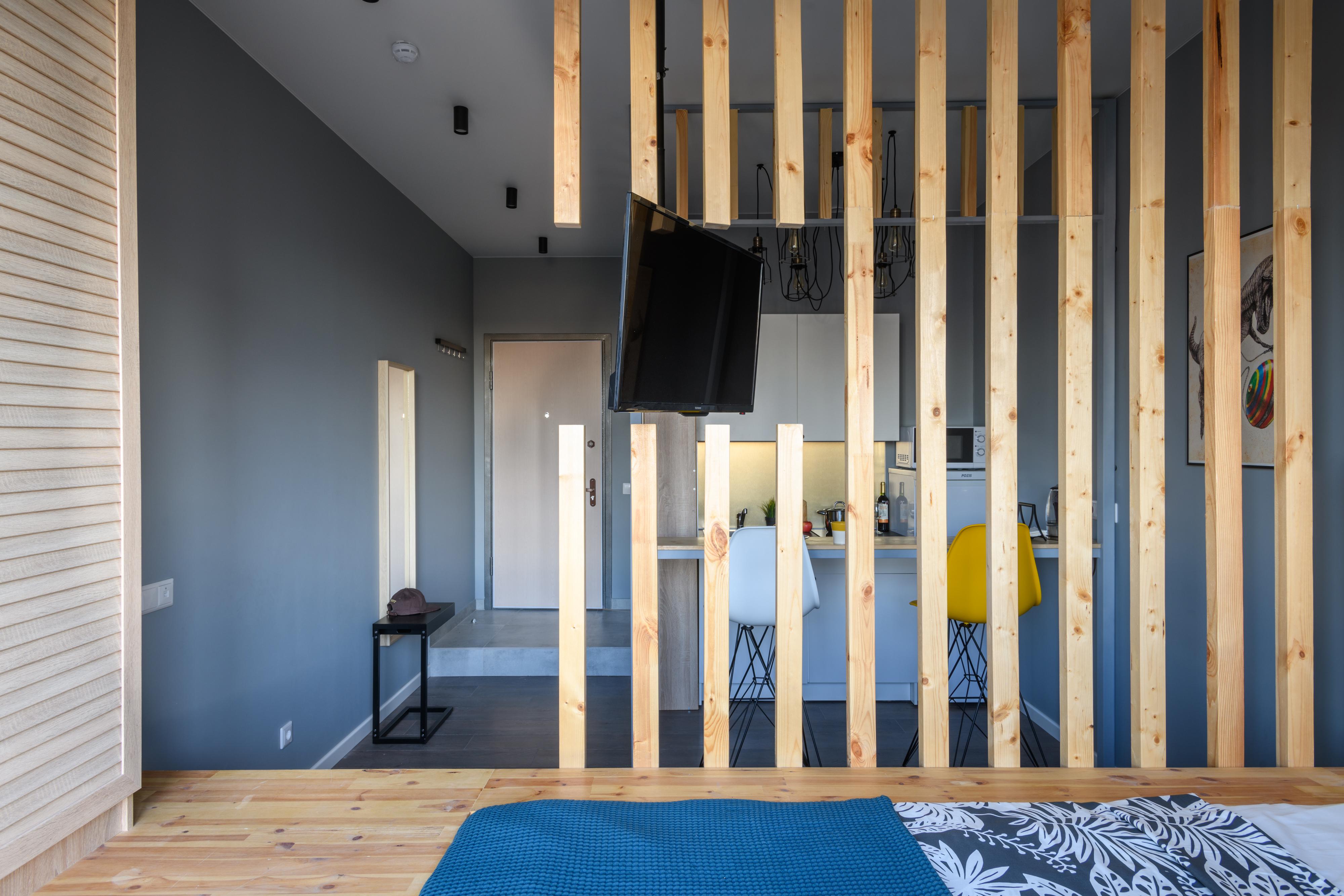 Интерьер спальни с в деревянном доме, балконом и зонированием рейками в стиле лофт